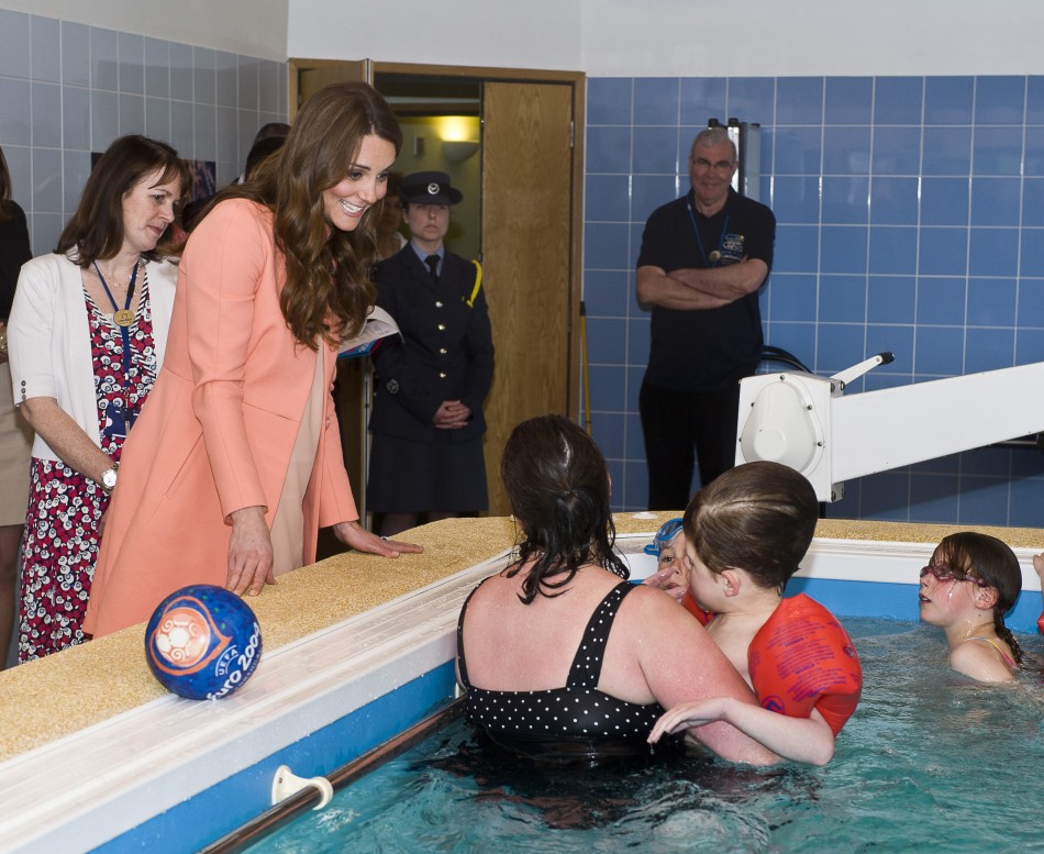 Catherine, Duchess of Cambridge, speaks with staff and children in the hydrotherapy pool