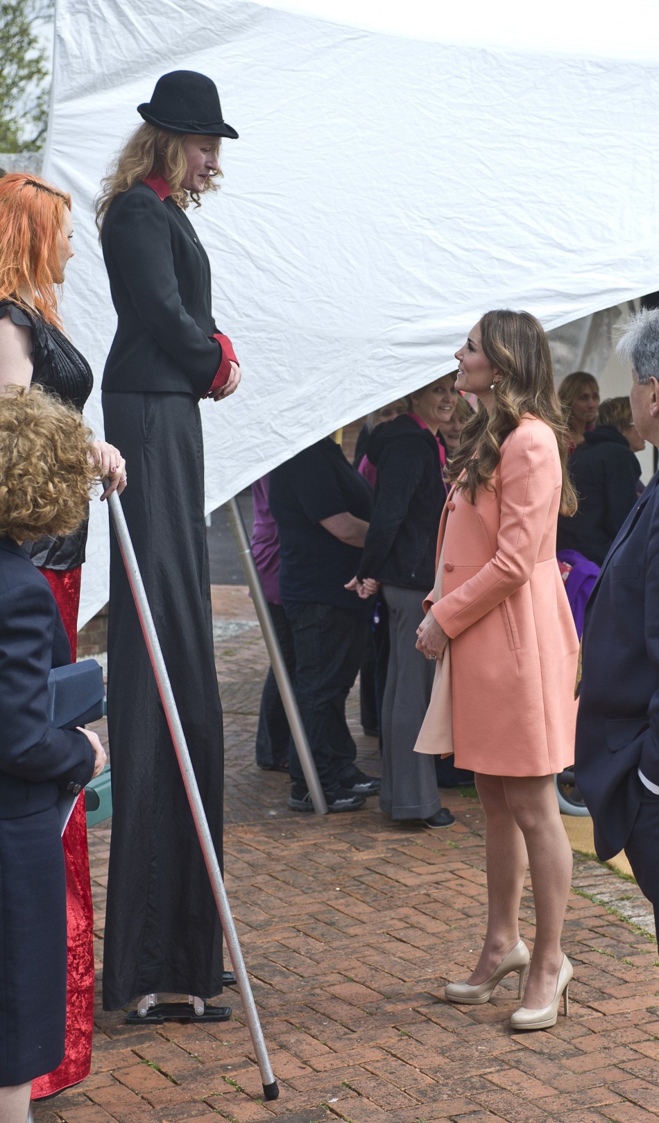 Catherine, Duchess of Cambridge, speaks with a woman on stilts