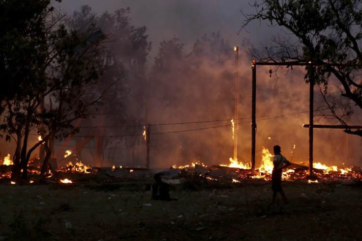 A man looks at buildings on fire during riots at Oakkan village, 100 km (60 miles) north of Yangon