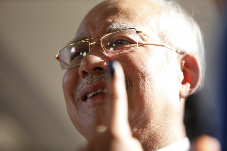 Malaysia's Prime Minister Najib Razak shows his finger with the ‘indelible’ ink to the media after casting his vote during the general elections