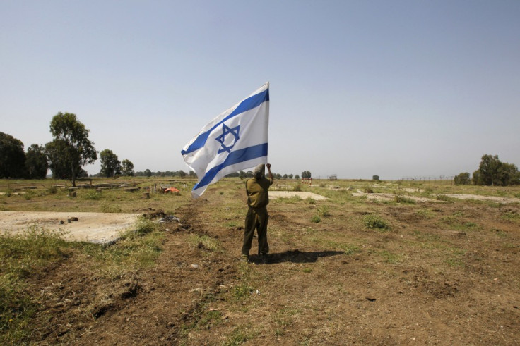 An Israeli soldier places a flag close to the ceasefire line between Israel and Syria