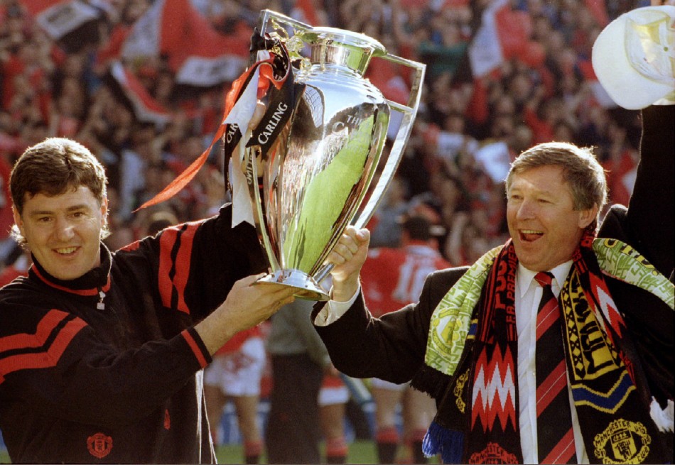 May 8 1994 Ferguson holds the Premier League trophy aloft with the then-assistant manager Brian Kidd at Old Trafford. The Scot led United to two back-to-back league titles, following Premier Leagues inception in 1992.