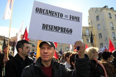 A man holds a sign reading: "Budget = hunger, unemployment" during an anti-austerity protest in front of Portugal's parliament in Lisbon November 27, 2012. (Photo: Reuters)