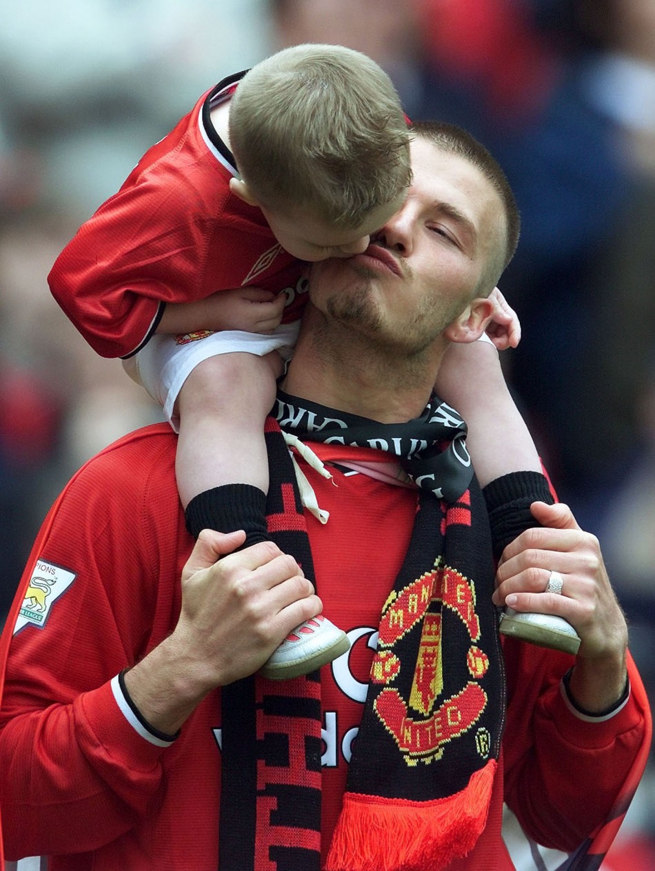 David Beckham gets a kiss from his son Brooklyn after winning the premiership at Old Trafford in Manchester, May 5, 2001.