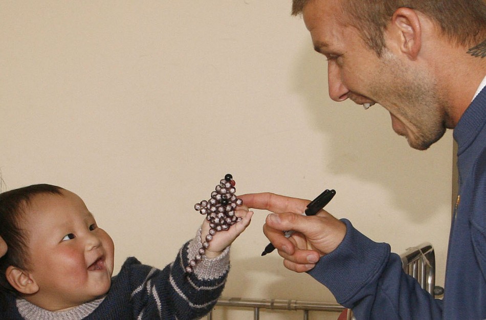 David Beckham plays with a boy in the childrens department of Xinhua hospital during a visit by him and his team mates in Shanghai March 4, 2008.