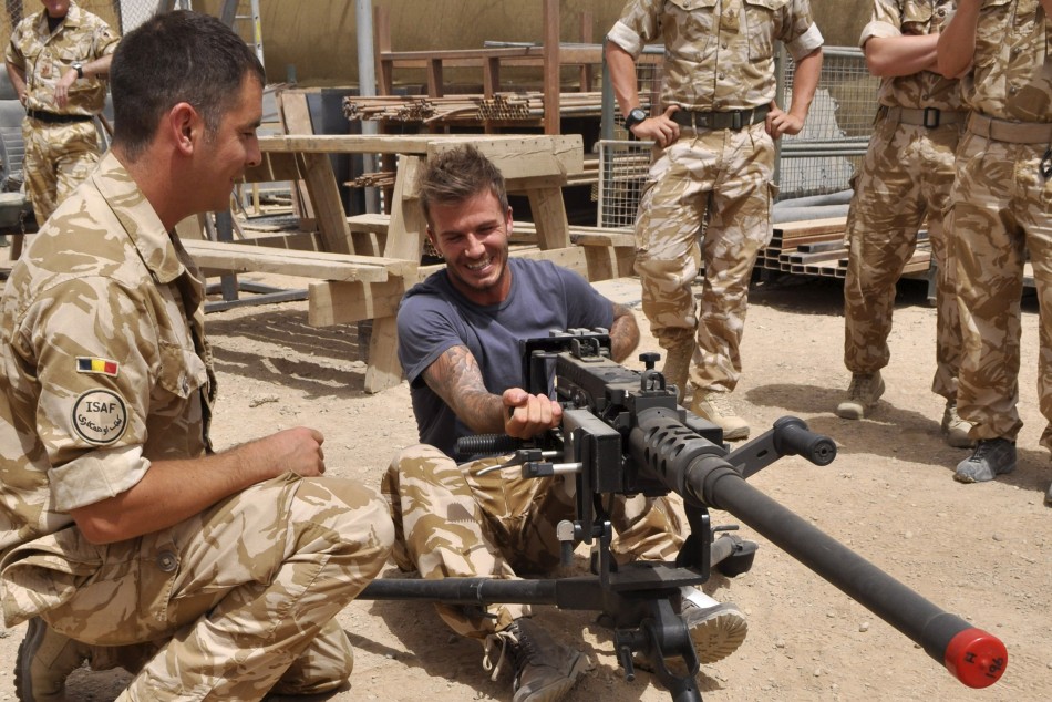 David Beckham C is seen cocking a Heavy Machine Gun during a visit to Camp Bastion, in Afghanistan in this May 22, 2010 handout photograph.