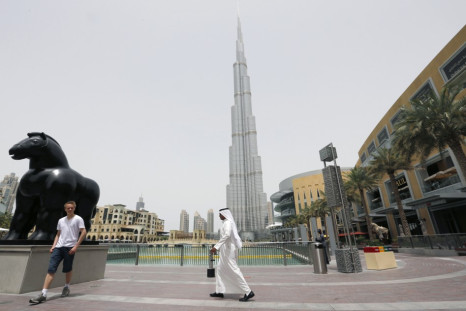 An Emirati man walks past a tourist posing for a photo near the Burj Khalifa, the tallest tower in the world, in Dubai May 9, 2013. (Photo: REUTERS)