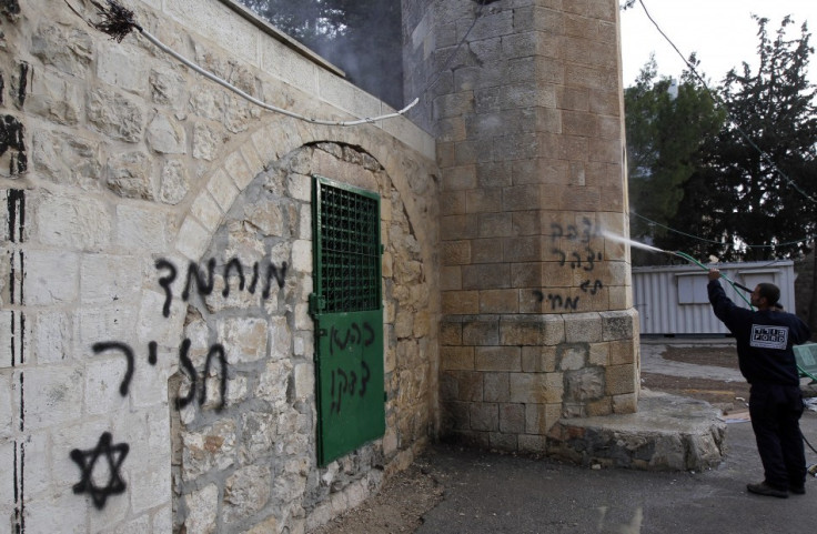 A labourer cleans graffiti off a vandalised mosque in Jerusalem December 14, 2011. The graffiti to the left reads in Hebrew "Mohammed is a pig."