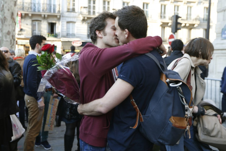 A gay couple kiss as people gather to celebrate after the French parliament approved a law allowing same-sex couples to marry and to adopt children,