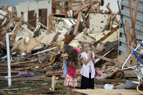 Two girls stand in rubble after a tornado struck Moore, Oklahoma, May 20, 2013. A 2-mile-wide (3-km-wide) tornado tore through the Oklahoma City suburb of Moore on Monday, killing at least 51 people while destroying entire tracts of homes, piling cars ato
