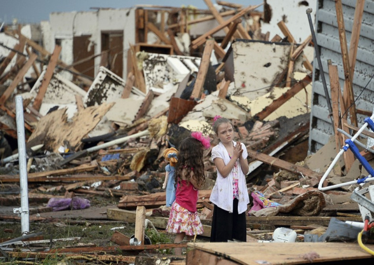 Two girls stand in rubble after a tornado struck Moore, Oklahoma, May 20, 2013. A 2-mile-wide (3-km-wide) tornado tore through the Oklahoma City suburb of Moore on Monday, killing at least 51 people while destroying entire tracts of homes, piling cars ato
