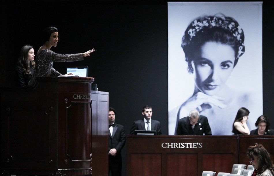 Christies auctioneer Andrea Fiuczynski conducts an auction of Elizabeth Taylors jewellery, clothing, art and memorabilia, near an image of the late actress at Christies auction house in New York, December 14, 2011