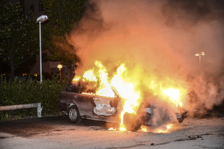 A car set on fire burns, following riots in the Stockholm suburb of Kista