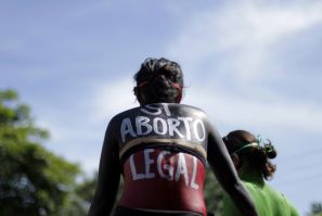 A woman sits in a float with "Yes abortion legal" written on her back during a protest in San Salvado