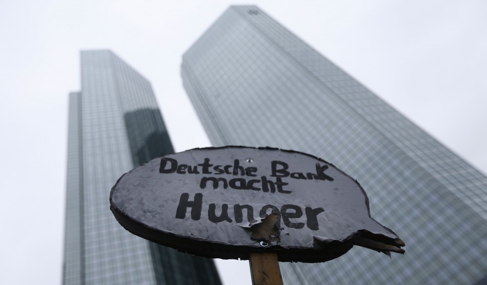 A protester holds a placard reading Deutsche Bank causes hunger in front of the headquarters of Germanys largest business bank, Deutsche Bank