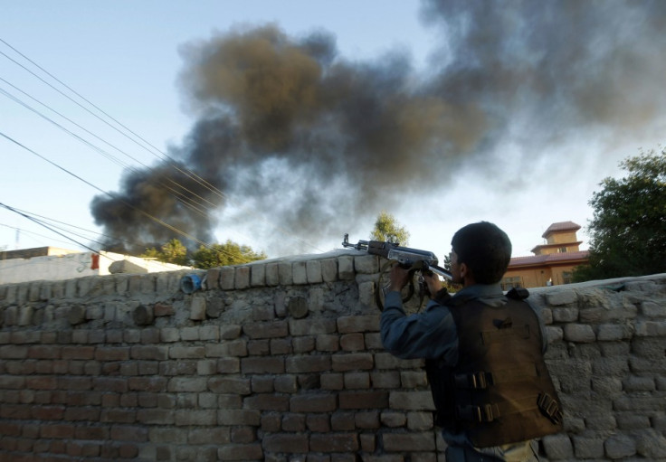 An Afghan policeman takes up position as smoke billows from the site of the ICRC compound