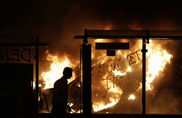 A protester walks past a burning car at Taksim Square in central Istanbul