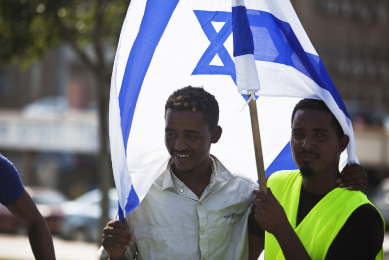 African migrants from Eritrea hold an Israeli flag during a protest near the Ministry of Defence in Tel Aviv