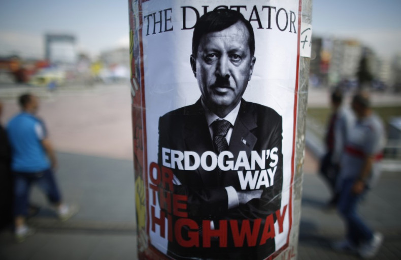 People walk past a poster depicting Turkish Prime Minister Tayyip Erdogan that has been pasted by demonstrators at Taksim Square in Istanbul