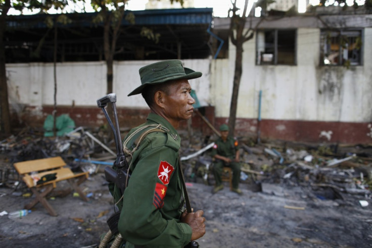 A soldier stands guard in front of a mosque that was burnt during a riot between Muslims and Buddhist in Lashio