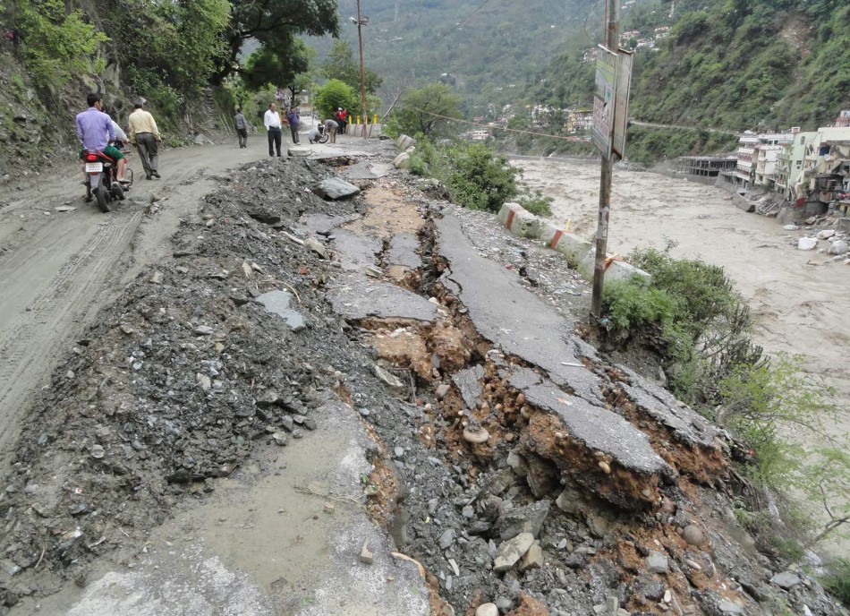 People walk along a damaged road after heavy rains in the Himalayan state of Uttarakhand June 17, 2013.