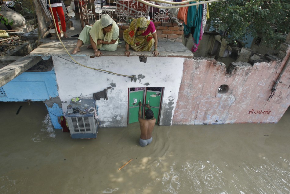 A man unlocks the door of his flooded house as other residents watch after a rise in the water level of river Yamuna in New Delhi June 19, 2013.