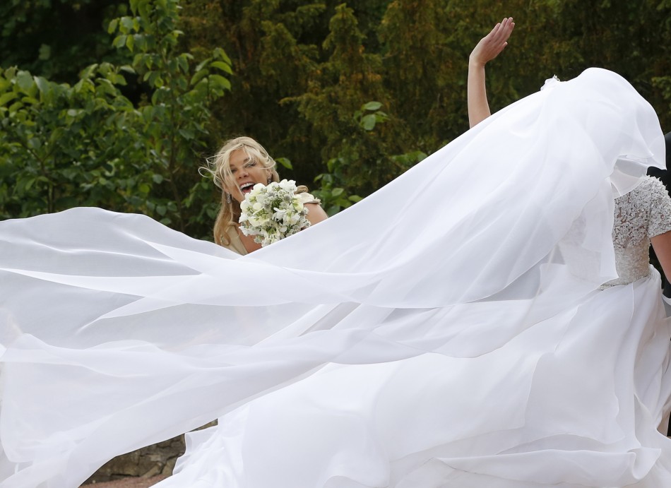 Bridesmaid Chelsy Davy reacts as wind blows the wedding dress of Melissa Percy