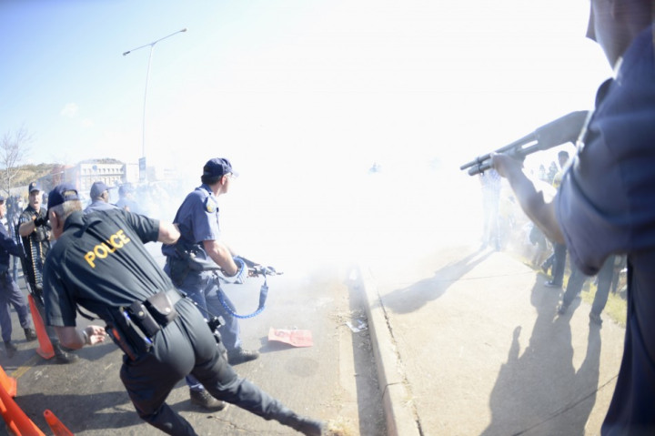 Police point weapons at protesters obscured by smoke at scene of protests at University of Johhanesburg Police point weapons at protesters obscured by smoke at scene of protests at University of Johhanesburg
