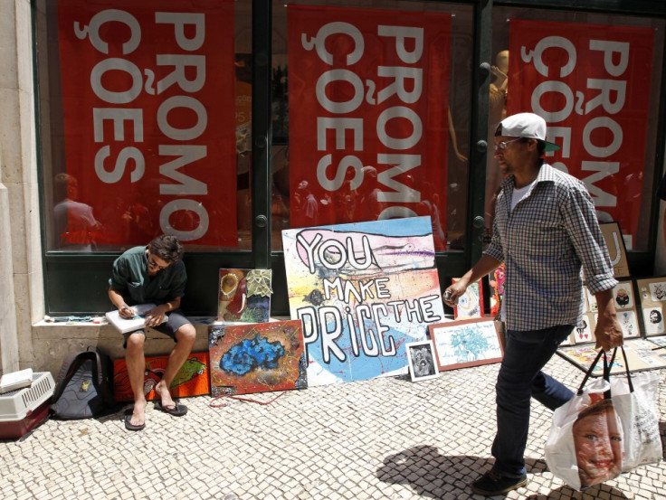 A man walks past a painter selling his work in front of a shop announcing promotions during the general strike in Lisbon June 27, 2013. (Photo: Reuters)