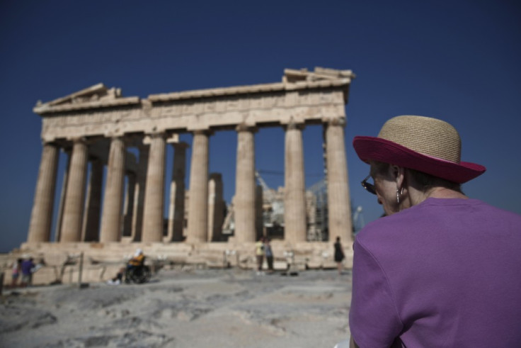 A tourist looks at the temple of the Parthenon atop the hill of the Acropolis in Athens