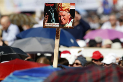 Faithful hold a poster of the late Pope John Paul II