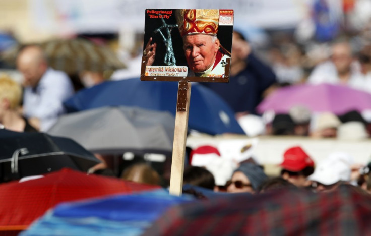 Faithful hold a poster of the late Pope John Paul II