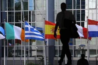 A pedestrian walks towards the (L-R) Irish, Greek, Spanish, French and Dutch national flags outside the European Parliament in Brussels (Photo: Reuters)