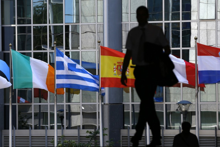 A pedestrian walks towards the (L-R) Irish, Greek, Spanish, French and Dutch national flags outside the European Parliament in Brussels (Photo: Reuters)