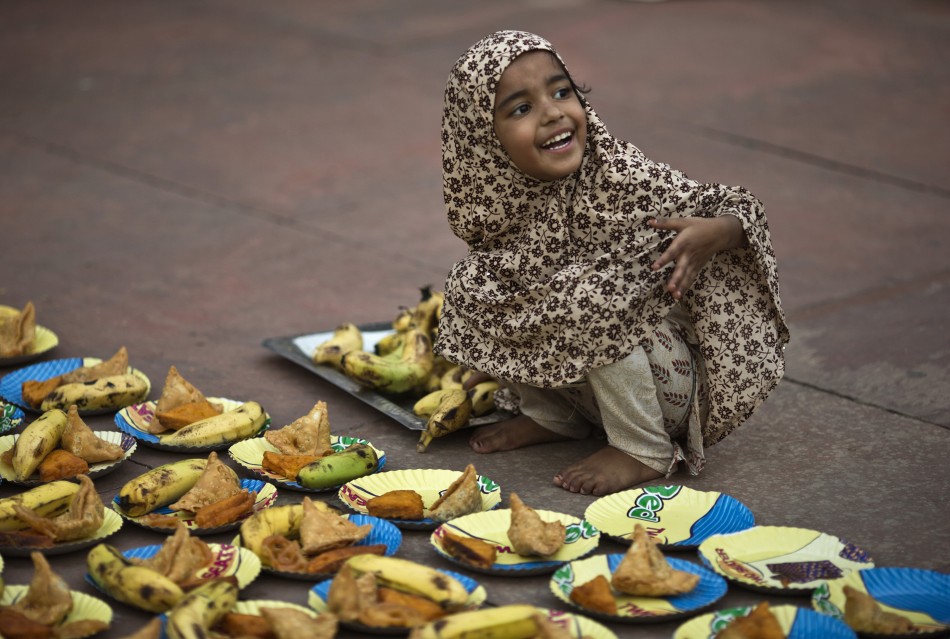 A Muslim girl arranges plates before iftar breaking fast meal on the first day of the holy month of Ramadan in India at the Jama Masjid Grand Mosque in the old quarters of Delhi