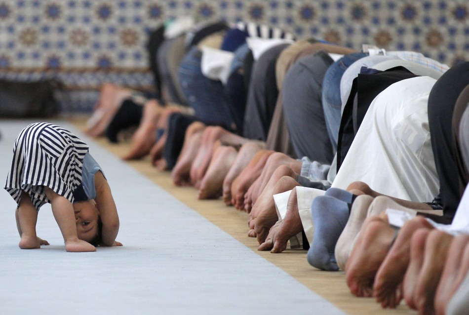 A child is seen near members of the Muslim community attending midday prayers at Strasbourg Grand Mosque in Strasbourg on the first day of Ramadan July 9, 2013. The Grand Mosque of Paris has fixed the first day of Ramadan