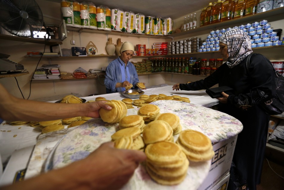 A Palestinian woman buys qatayef, a dessert traditionally eaten during the Muslim holy fasting month of Ramadan, on the first day of Ramadan in the West Bank city of Ramallah