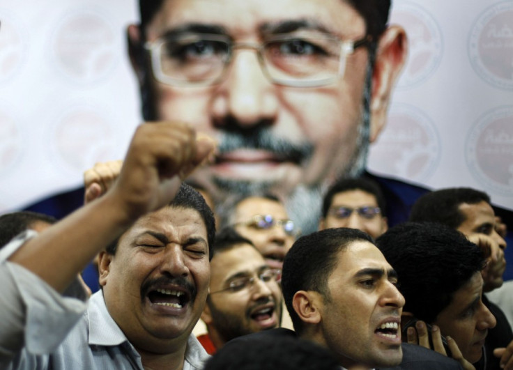 Supporters of the Muslim Brotherhood's presidential candidate Mohamed Morsi celebrate in front of his picture at his headquarters in Cairo (Reuters)