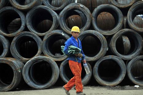 A labourer walks past piles of steel coils at a steel wholesale market in Shenyang