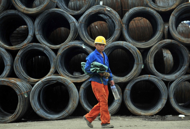 A labourer walks past piles of steel coils at a steel wholesale market in Shenyang