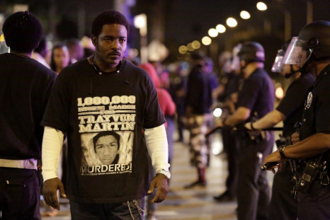 A protester defiantly walks past a line of Los Angeles Police officers as they try to remove protesters from the streets, following the George Zimmerman verdict