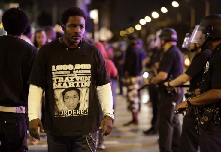 A protester defiantly walks past a line of Los Angeles Police officers as they try to remove protesters from the streets, following the George Zimmerman verdict