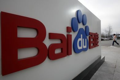 A woman walks past the company logo of Baidu at its headquarters in Beijing