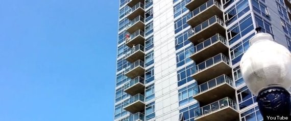A woman dangles from the 14th floor of The Mark condominium building in San Diego (Youtube)