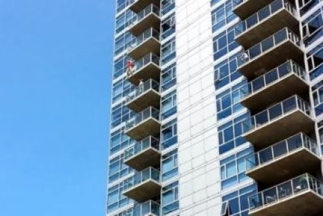 A woman dangles from the 14th floor of The Mark condominium building in San Diego (Youtube)