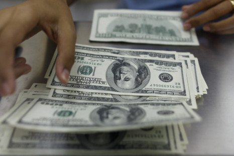 A woman counts U.S. dollars at a money changer