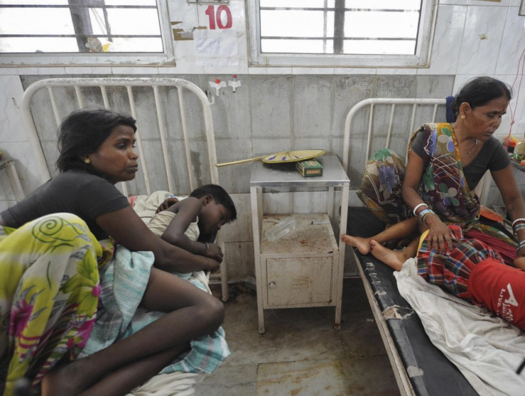 Women sit next to their sick children who consumed the contaminated meal (Reuters)