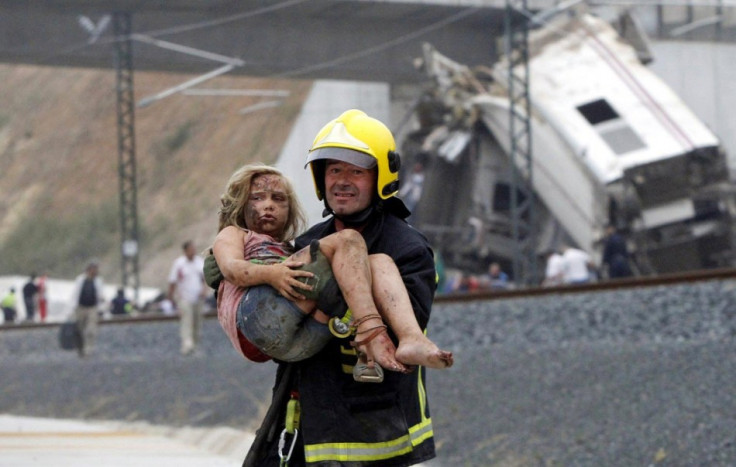 A rescue worker carries a little girl to safety from the train wreck in Santiago de Compostela