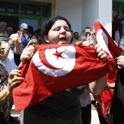 Assassinated Tunisian opposition politician Mohamed Brahmi's daughter Balkis (C) holds a Tunisian flag as she mourns his death in Tunis