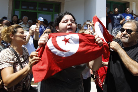 Assassinated Tunisian opposition politician Mohamed Brahmi's daughter Balkis (C) holds a Tunisian flag as she mourns his death in Tunis